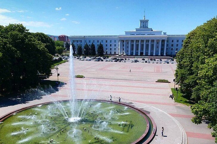 Panoramic view of Nalchik city with tree-lined boulevard and mountains in background