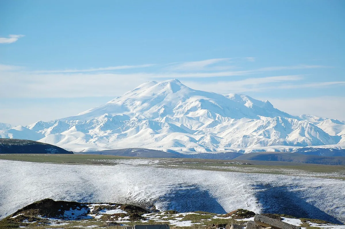 Snow-covered twin peaks of Mount Elbrus, called Oshhamakho by Circassians, under a blue sky